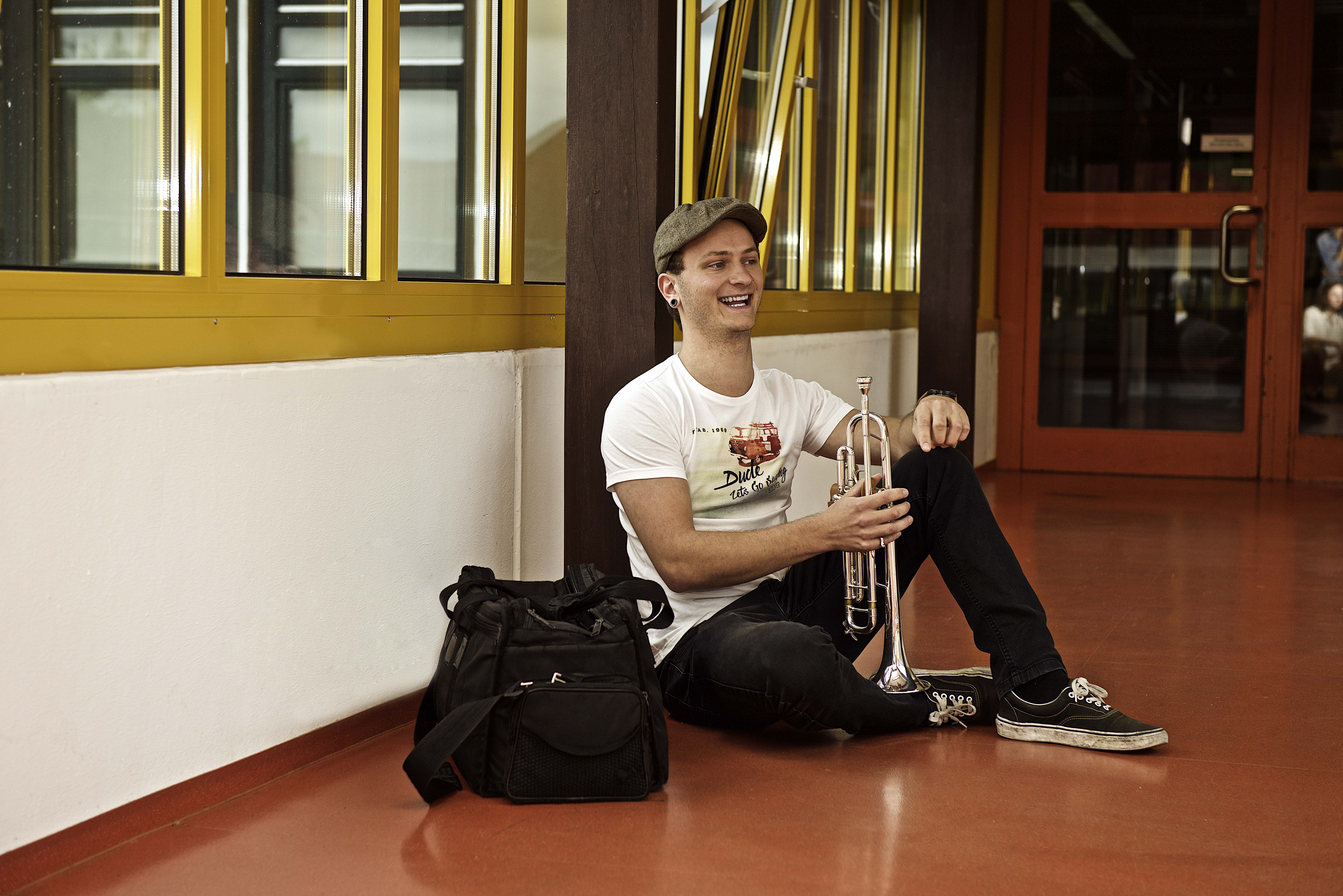 Ein Student mit Instrument, unterwegs in der Universität