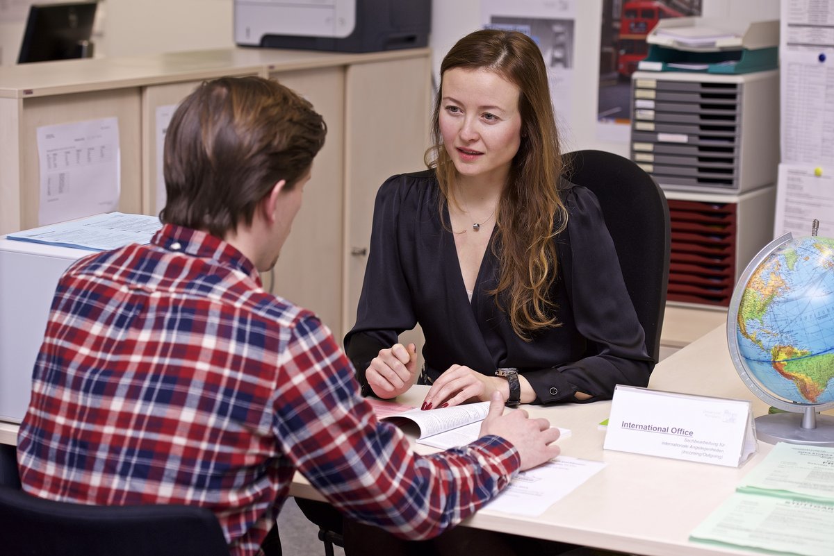 Ein Student lässt sich am Tisch des International Office im SSZ von einer Mitarbeiterin beraten