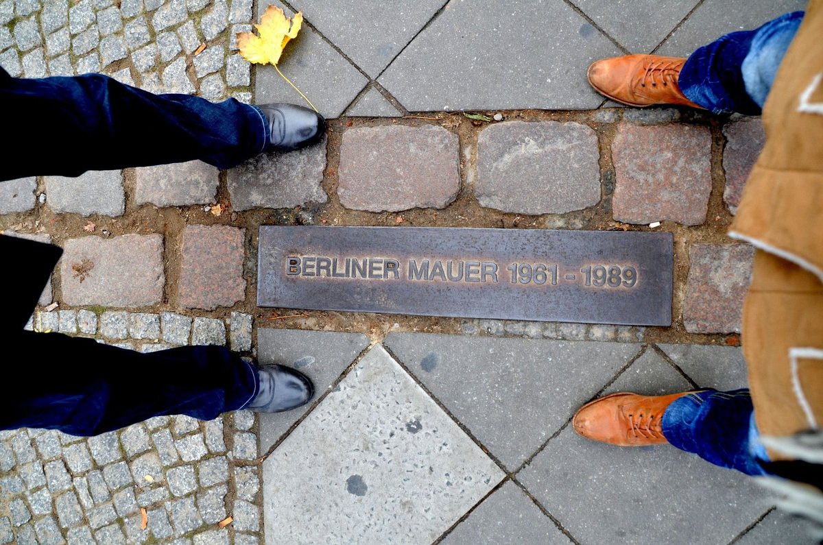 Two persons are standing  on the former border between East and West Germany.