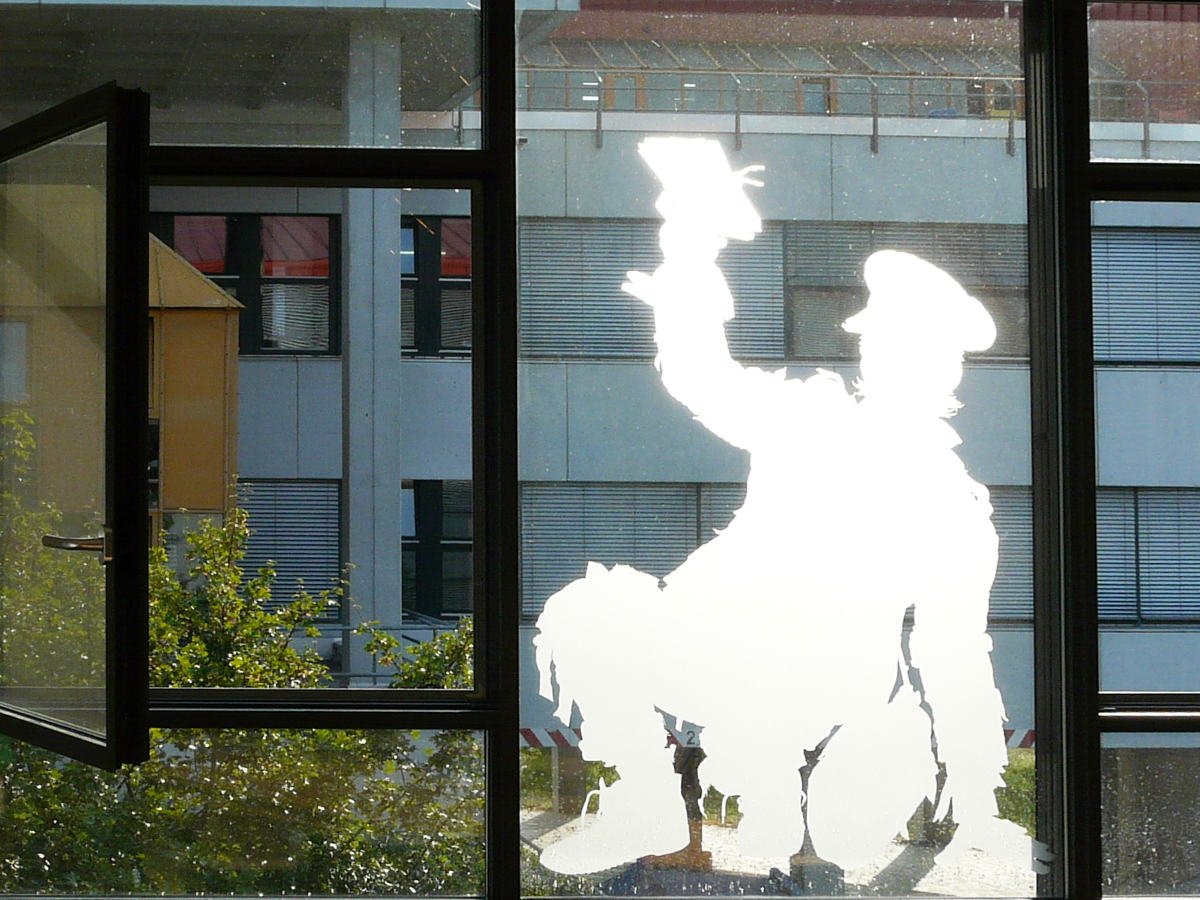Kunst am Bau: Silhouette eines Briefträgers auf einer der Scheiben des Y-Gebäudes