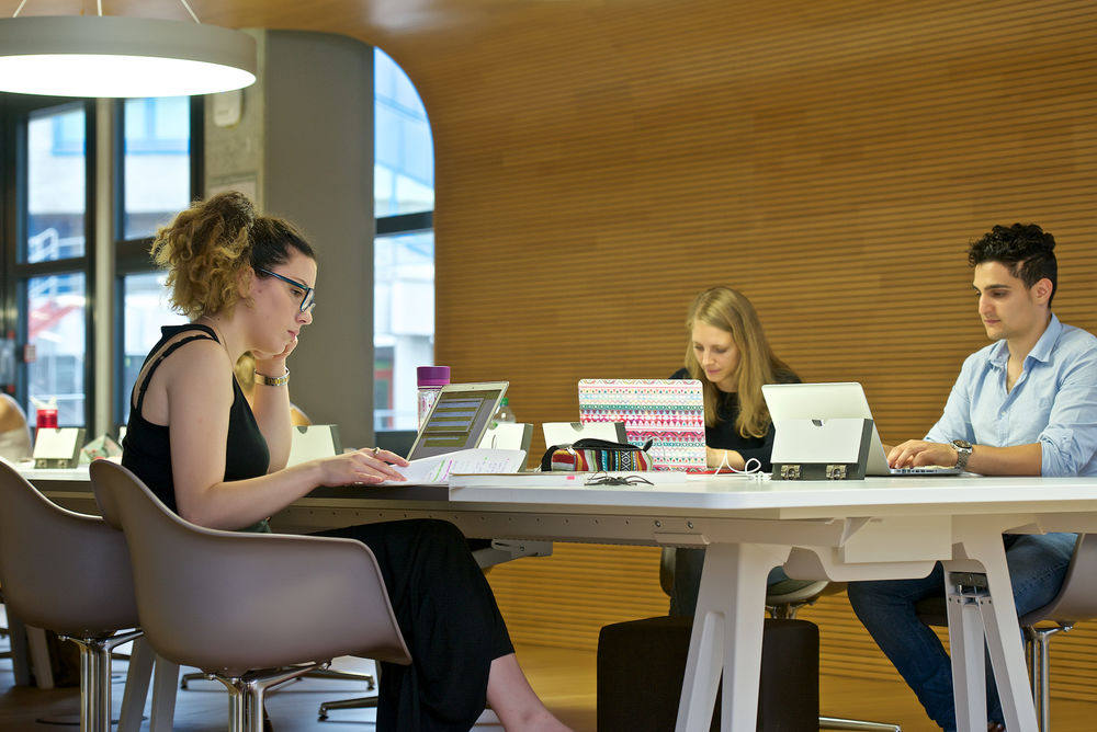 Studierende sitzen im Lesesaal der Bibliothek und arbeiten an ihren Laptops.